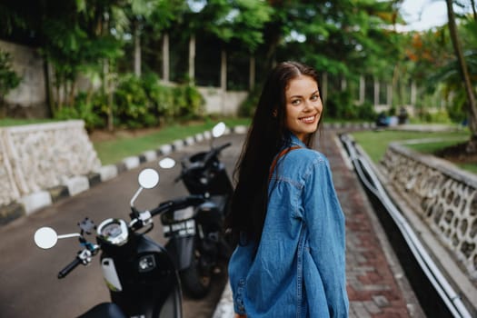 Portrait of a woman brunette smile with teeth walking outside against a backdrop of palm trees in the tropics, summer vacations and outdoor recreation, the carefree lifestyle of a freelance student. High quality photo