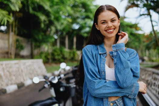 Portrait of a woman brunette smile with teeth walking outside against a backdrop of palm trees in the tropics, summer vacations and outdoor recreation, the carefree lifestyle of a freelance student. High quality photo