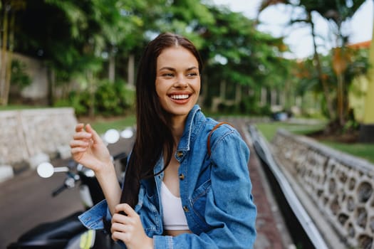 Portrait of a woman brunette smile with teeth walking outside against a backdrop of palm trees in the tropics, summer vacations and outdoor recreation, the carefree lifestyle of a freelance student. High quality photo