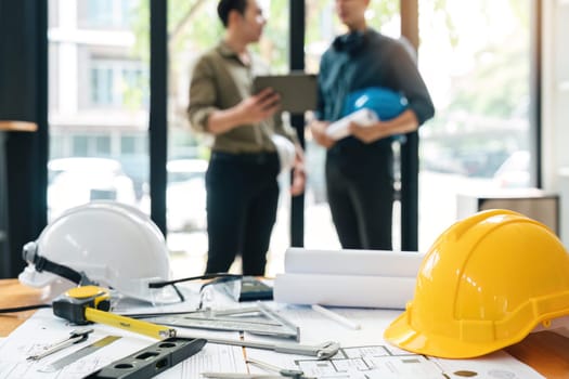 Engineer teams meeting working together holding worker helmets on construction site in modern city.Asian industry professional team.