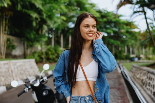 Portrait of a woman brunette smile with teeth walking outside against a backdrop of palm trees in the tropics, summer vacations and outdoor recreation, the carefree lifestyle of a freelance student. High quality photo