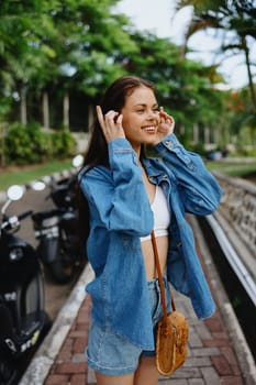 Portrait of a woman brunette smile with teeth walking outside against a backdrop of palm trees in the tropics, summer vacations and outdoor recreation, the carefree lifestyle of a freelance student. High quality photo