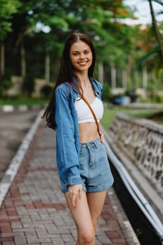 Portrait of a woman brunette smile with teeth walking outside against a backdrop of palm trees in the tropics, summer vacations and outdoor recreation, the carefree lifestyle of a freelance student. High quality photo