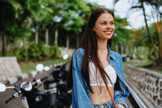 Portrait of a woman brunette smile with teeth walking outside against a backdrop of palm trees in the tropics, summer vacations and outdoor recreation, the carefree lifestyle of a freelance student. High quality photo