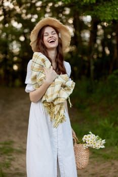 portrait of a happy woman in a light dress and a wicker hat with a plaid in her hands. High quality photo