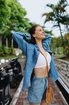 Portrait of a woman brunette smile with teeth walking outside against a backdrop of palm trees in the tropics, summer vacations and outdoor recreation, the carefree lifestyle of a freelance student. High quality photo