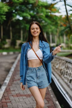 Portrait of a woman brunette smile with teeth walking outside against a backdrop of palm trees in the tropics, summer vacations and outdoor recreation, the carefree lifestyle of a freelance student. High quality photo