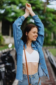 Portrait of a woman brunette smile with teeth walking outside against a backdrop of palm trees in the tropics, summer vacations and outdoor recreation, the carefree lifestyle of a freelance student. High quality photo