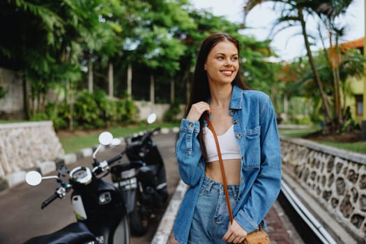 Portrait of a woman brunette smile with teeth walking outside against a backdrop of palm trees in the tropics, summer vacations and outdoor recreation, the carefree lifestyle of a freelance student. High quality photo