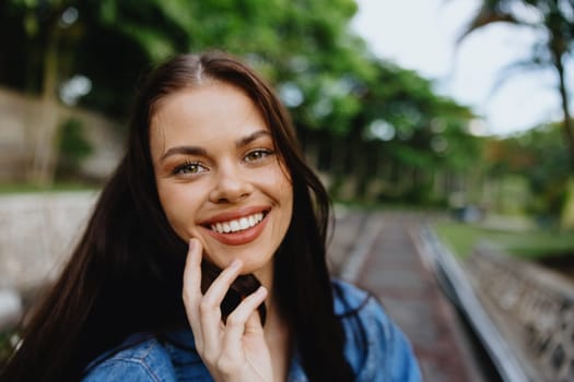 Portrait of a woman brunette smile with teeth walking outside against a backdrop of palm trees in the tropics, summer vacations and outdoor recreation, the carefree lifestyle of a freelance student. High quality photo