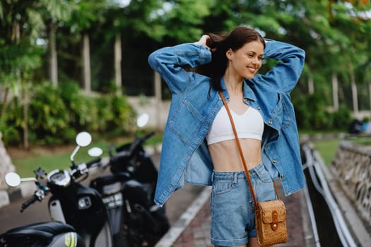 Portrait of a woman brunette smile with teeth walking outside against a backdrop of palm trees in the tropics, summer vacations and outdoor recreation, the carefree lifestyle of a freelance student. High quality photo