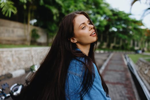 Portrait of a woman brunette smile with teeth walking outside against a backdrop of palm trees in the tropics, summer vacations and outdoor recreation, the carefree lifestyle of a freelance student. High quality photo