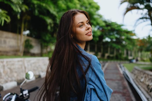Portrait of a woman brunette smile with teeth running down the street against a backdrop of palm trees in the tropics, summer vacations and outdoor recreation, the carefree lifestyle of a freelance student. High quality photo