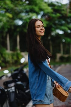 Portrait of a woman brunette smile with teeth running down the street against a backdrop of palm trees in the tropics, summer vacations and outdoor recreation, the carefree lifestyle of a freelance student. High quality photo