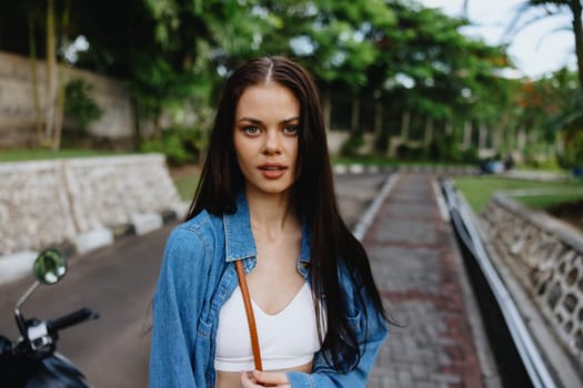 Portrait of a woman brunette smile with teeth walking outside against a backdrop of palm trees in the tropics, summer vacations and outdoor recreation, the carefree lifestyle of a freelance student. High quality photo