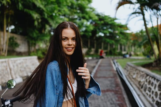 Portrait of a woman brunette smile with teeth running down the street against a backdrop of palm trees in the tropics, summer vacations and outdoor recreation, the carefree lifestyle of a freelance student. High quality photo