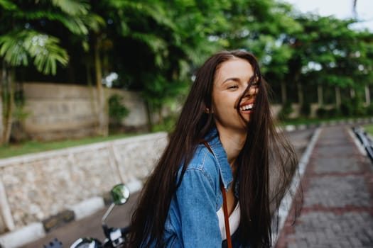 Portrait of a woman brunette smile with teeth walking outside against a backdrop of palm trees in the tropics, summer vacations and outdoor recreation, the carefree lifestyle of a freelance student. High quality photo