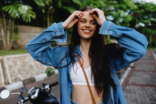 Portrait of a woman brunette smile with teeth walking outside against a backdrop of palm trees in the tropics, summer vacations and outdoor recreation, the carefree lifestyle of a freelance student. High quality photo