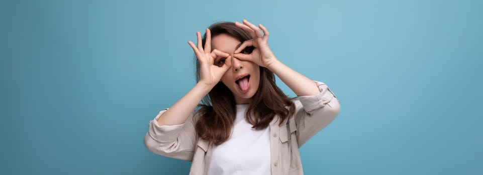 panoramic photo of a joyful cheerful brunette young female adult in a shirt and jeans on a background with copy space.