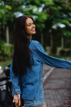 Portrait of a woman brunette smile with teeth running down the street against a backdrop of palm trees in the tropics, summer vacations and outdoor recreation, the carefree lifestyle of a freelance student. High quality photo