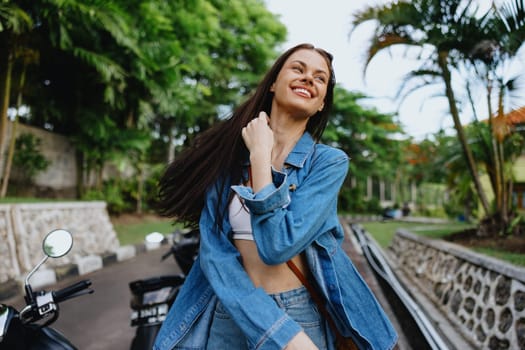 Portrait of a woman brunette smile with teeth walking outside against a backdrop of palm trees in the tropics, summer vacations and outdoor recreation, the carefree lifestyle of a freelance student. High quality photo