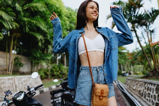 Portrait of a woman brunette smile with teeth walking outside against a backdrop of palm trees in the tropics, summer vacations and outdoor recreation, the carefree lifestyle of a freelance student. High quality photo