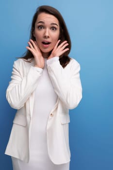 surprised confused pretty brunette young woman in a dress and jacket with a grimace.