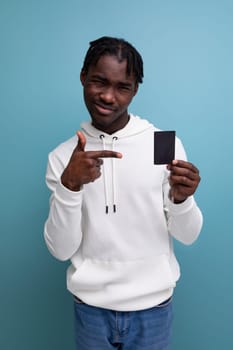 optimist smiling young african guy in a white sweatshirt shows a plastic map with a mockup.