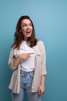 surprised emotional brunette 30 year old female person dressed in a shirt and jeans looks away on a blue background.