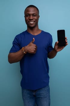 handsome 25c african guy in casual blue t-shirt showing smartphone screen.
