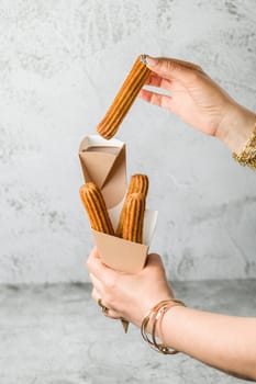 Woman taking churros from a cone and dipping it in chocolate sauce