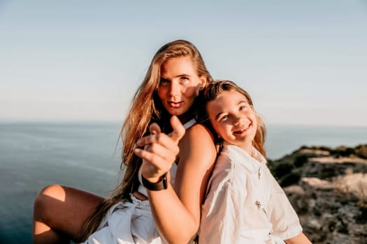 Close up portrait of mom and her teenage daughter hugging and smiling together over sunset sea view. Beautiful woman relaxing with her child.