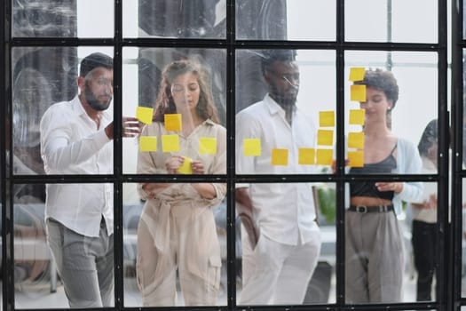 colleagues discuss and stick notes on the glass in the office