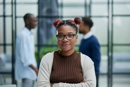 She is standing in a modern office with her colleagues in the background.