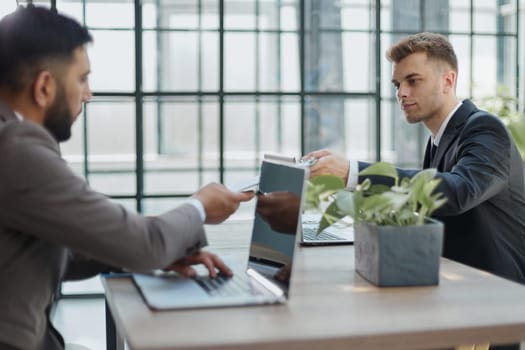 Discussing the problem. Two confident business man discussing something on the computer