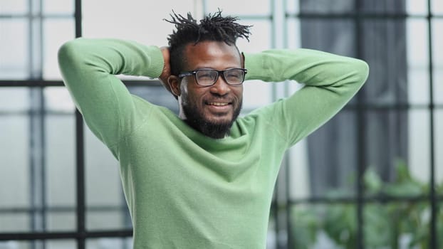 a young man in a green sweatshirt clasped his hands behind his head.