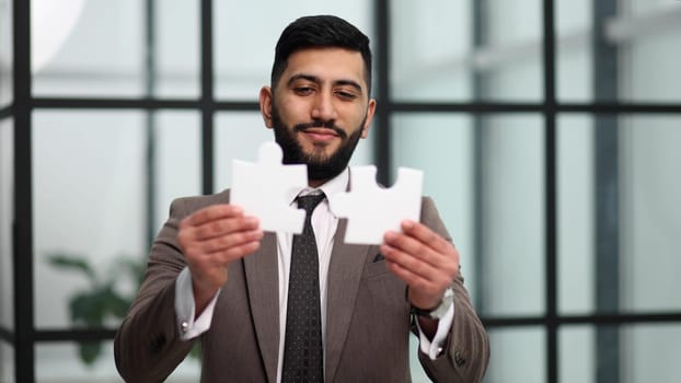 Business puzzle, strategy and marketing. Businessman shows silver pieces of the puzzle