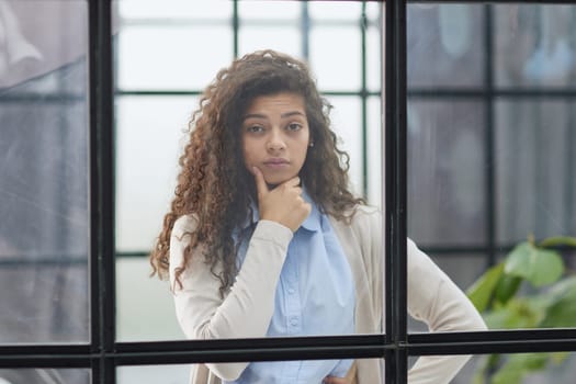 from behind the glass. young business woman thinking about something