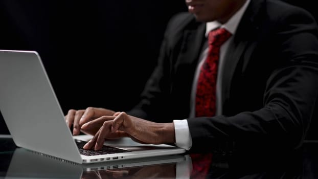 uses a laptop on a wooden table in a dark room.