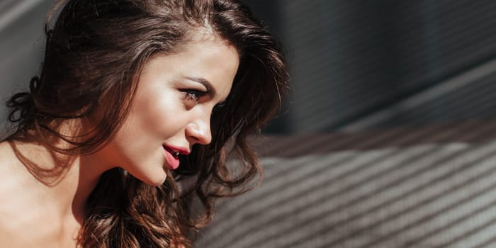 Baner close-up of the seductive face of the brunette with beautiful makeup and sexy lips. luxurious hairstyle and flirtatious look.
