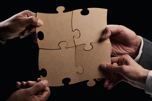 See the big picture. Close-up of an unknown business man holding three pieces of a puzzle together.