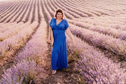 Woman lavender field sunset. Romantic woman walks through the lavender fields. illuminated by sunset sunlight. She is wearing a blue dress with a hat