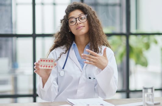 Portrait of young female doctor in white coat at workplace