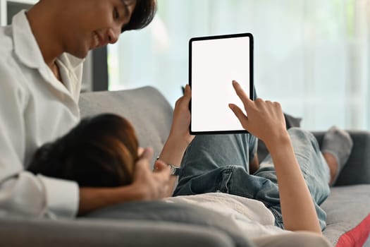 Loving homosexual couple embracing and using digital tablet on couch. LGBT, love and lifestyle relationship concept.