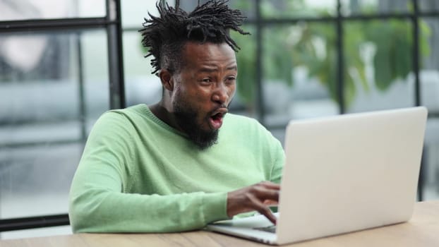 Close-up of a laughing african american man looking into a laptop