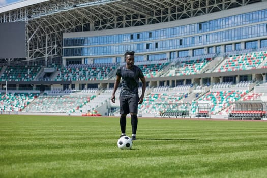 African American man playing football on the stadium field.