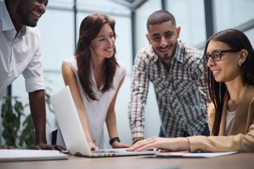 Diverse group of coworkers listening to a presentation during a staff meeting around a table in an office