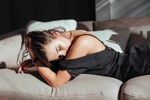 Portrait of a sexy brunette in a black dress on a dark background. girl takes off her dress slowly in the bedroom.