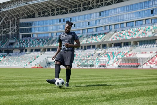 African American man playing football on the stadium field. A man runs with a soccer ball across the field.