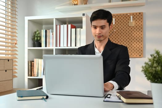 Image of startup businessman using laptop and working with graph and statistic document on desk at workplace.